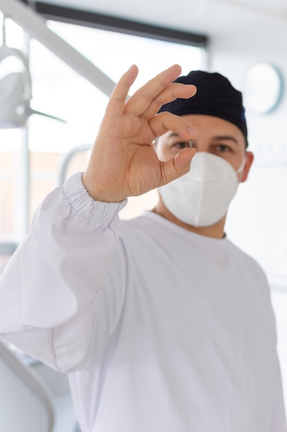 Concéntrese en la mano de un dentista sosteniendo un tornillo de implante dental mientras su cara está desenfocada en el fondo