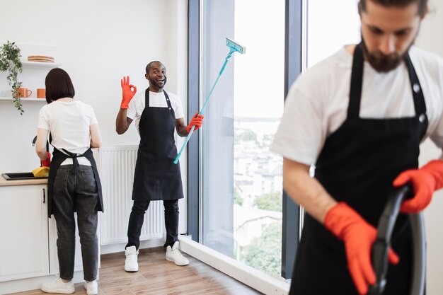 Concéntrese en el positivo trabajador afroamericano limpiando la ventana panorámica
