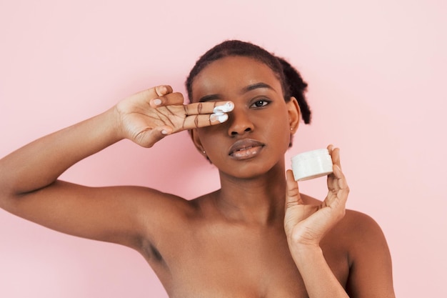 Concepção de cuidados com a pele Retrato de uma jovem afro-americana que está contra o fundo rosa