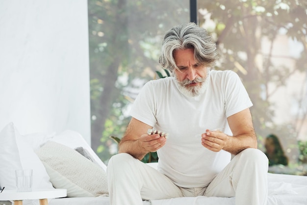 Concepção de doença e vírus Homem moderno elegante sênior com cabelos grisalhos e barba dentro de casa