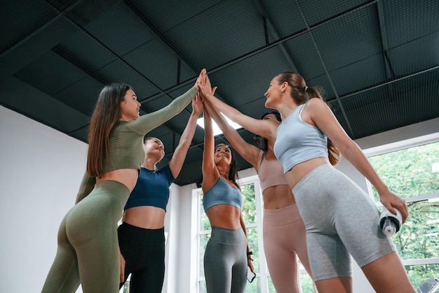 Concepção de sucesso dando high fives Grupo de mulheres praticando fitness na academia