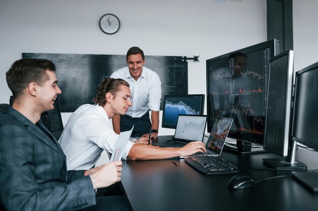 Concepção do trabalho em equipe A equipe de corretores da bolsa trabalha em um escritório moderno com muitas telas de exibição