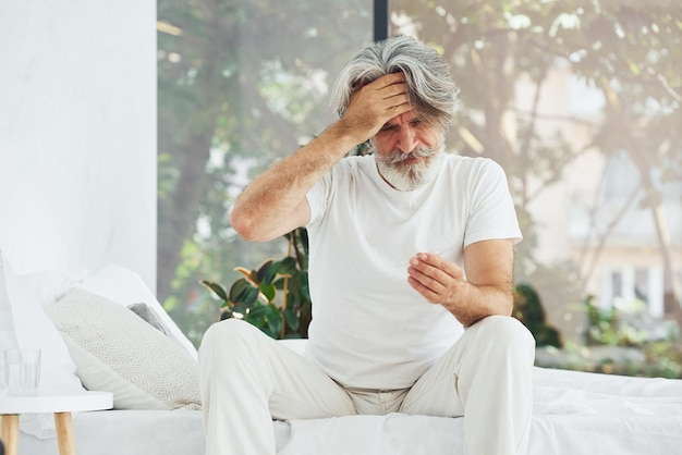 Concepción de enfermedad y virus Hombre moderno con estilo senior con cabello gris y barba en el interior