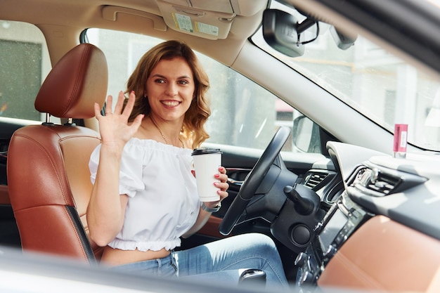 Concepción del éxito Mujer joven con ropa informal está sentada en su auto durante el día