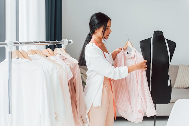 Concepción de la moda La costurera está en su oficina con ropa diferente