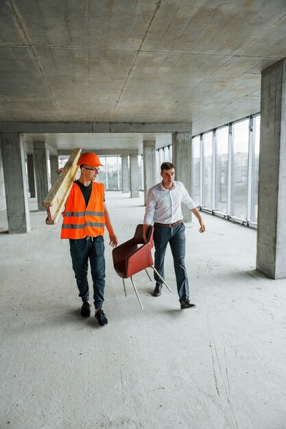 Concepción del trabajo en equipo El hombre de traje y manitas con ropa protectora naranja está trabajando en la construcción