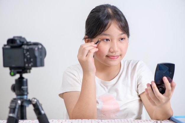 Concept beauty girl blogger mujer asiática dibuja cejas revisión en transmisión en vivo aislada sobre fondo blanco