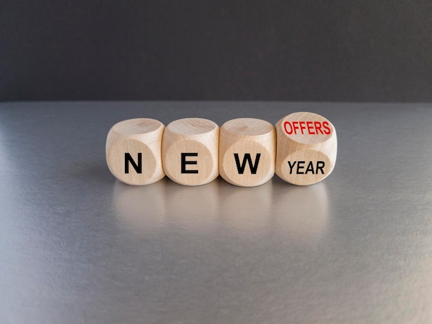 Foto concept palabra nuevo año nuevas ofertas en hermosos cubos de madera hermosa mesa gris fondo negro