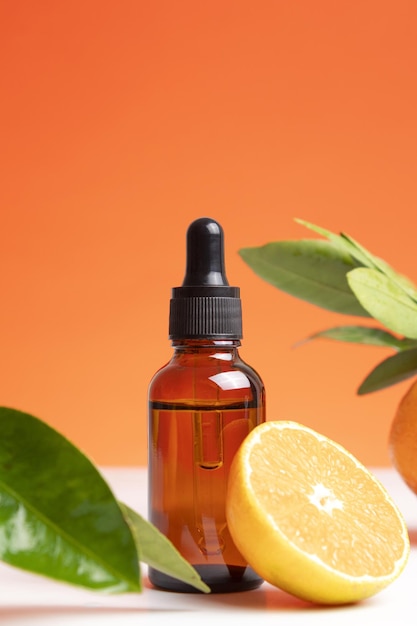 Concepto de aceite esencial de naranja orgánico natural para el cuidado de la salud de la cara y el cuerpo de la piel Tratamiento de desintoxicación de aromaterapia hidratante efecto antiestrés Fruta fresca hojas verdes fondo naranja