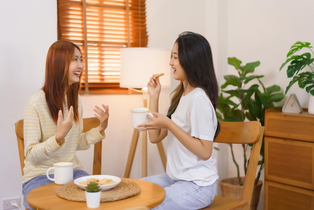 Concepto de actividad en casa Una pareja de lesbianas LGBT bebe café y come galletas mientras hablan juntas
