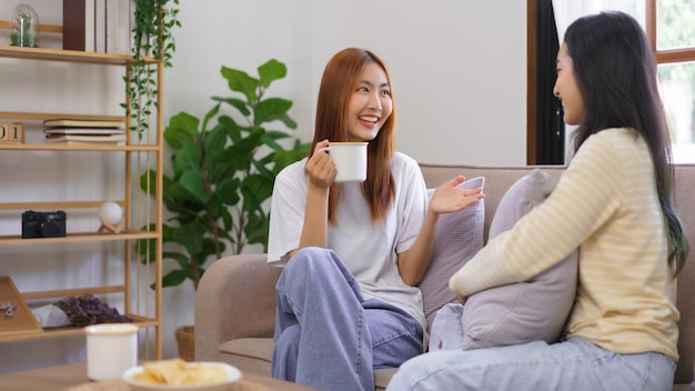 Concepto de actividad en casa Pareja de lesbianas LGBT tomando café y hablando juntas en la sala de estar