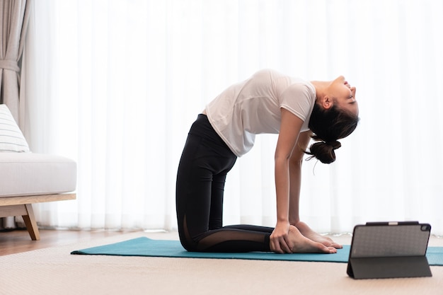 Concepto de actividad productiva una mujer adulta joven practicando la flexibilidad de su cuerpo haciendo ejercicio mat pilates.