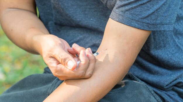 El concepto de adicto con el hombre usa una jeringa para disparar la droga de contrabando al cuerpo.