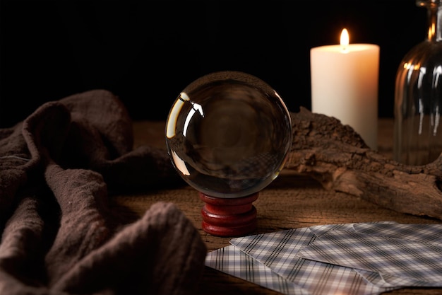 concepto de adivinación en una mesa de madera y una vela con una bola de cristal y un fondo de cartas del tarot