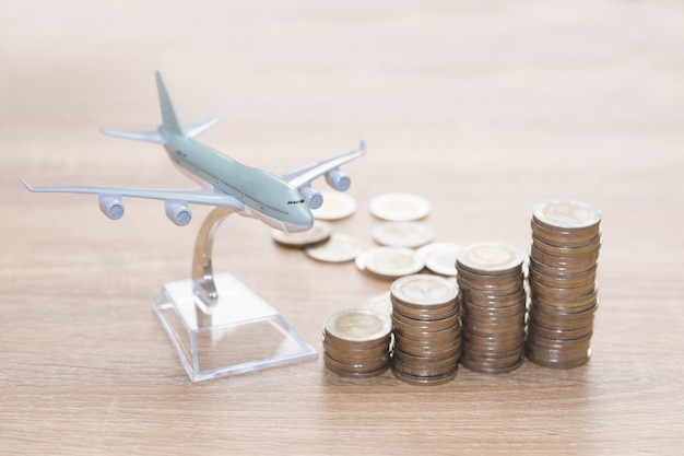 Concepto de ahorro de dinero de vacaciones - Apilamiento de monedas para viajar con modelo de avión