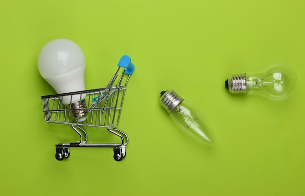 Foto concepto de ahorro de energía. carrito de la compra de supermercado y bombillas en verde