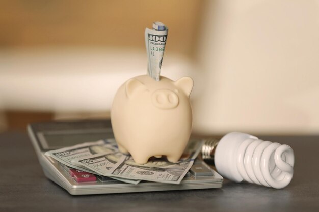 Concepto de ahorro de energía eléctrica Hucha de cerámica con calculadora y dinero en la mesa