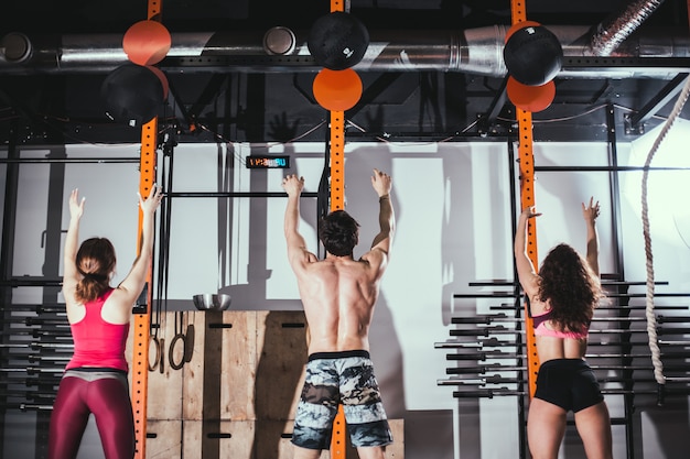 Concepto de ajuste, deporte y ejercicio: personas con balones medicinales entrenando en el gimnasio