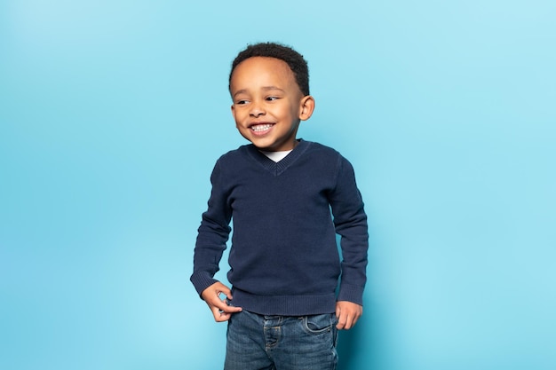 Concepto de alegría y felicidad de la infancia de la gente Adorable niño negro de buen humor posando sobre fondo azul