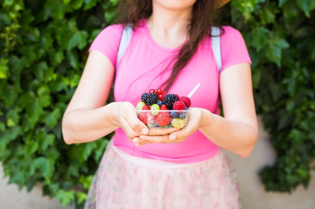 Concepto de alimentación, dieta, comida vegetariana y personas saludables - cerca de las manos de la mujer sosteniendo bayas al aire libre.