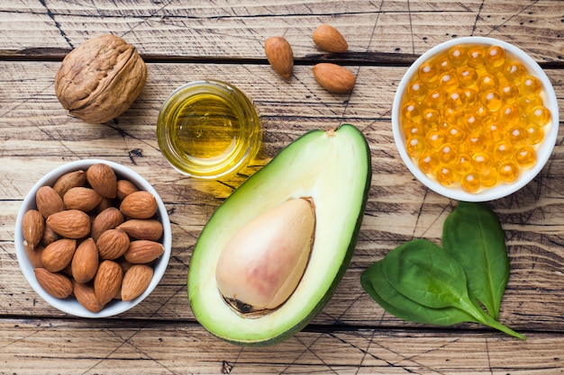 Concepto de alimentos saludables productos antioxidantes aguacate, nueces y aceite de pescado, toronja sobre fondo de madera.