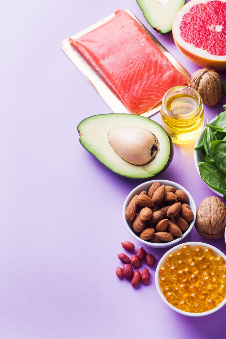 Concepto de alimentos saludables, productos antioxidantes: pescado y aguacate, nueces y aceite de pescado, pomelo sobre fondo rosa. Copia espacio