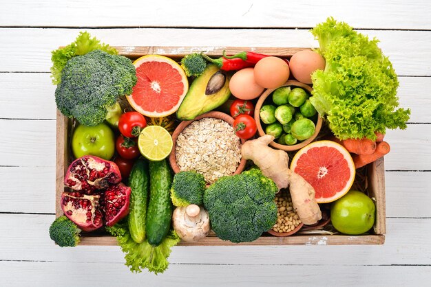 El concepto de alimentos saludables Verduras frescas nueces y frutas en una caja de madera Sobre un fondo de madera Vista superior Espacio de copia