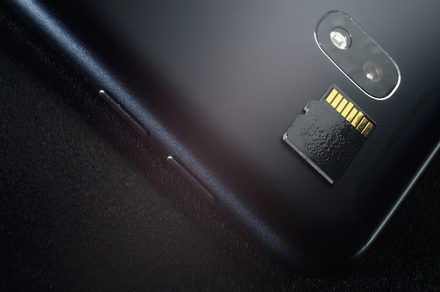 Concepto de almacenamiento de memoria flash: tarjeta Micro SD en el fondo de un teléfono inteligente. Una tarjeta de memoria se utiliza para almacenar información digital en dispositivos electrónicos portátiles como teléfonos móviles, tabletas, etc.