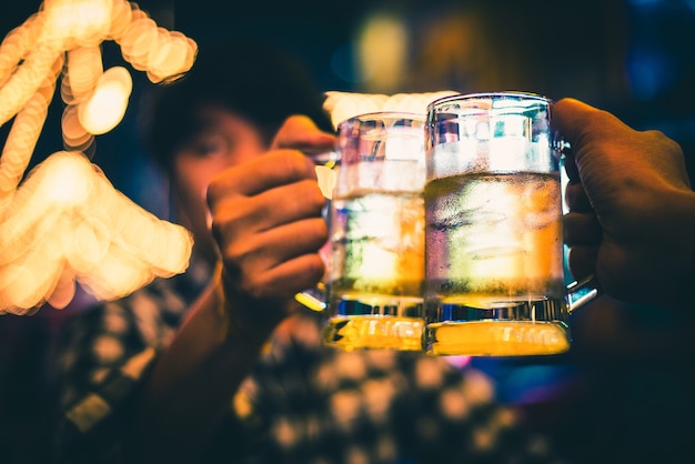 concepto de amistad y celebración - amigos varones felices bebiendo cerveza tintineo gafas