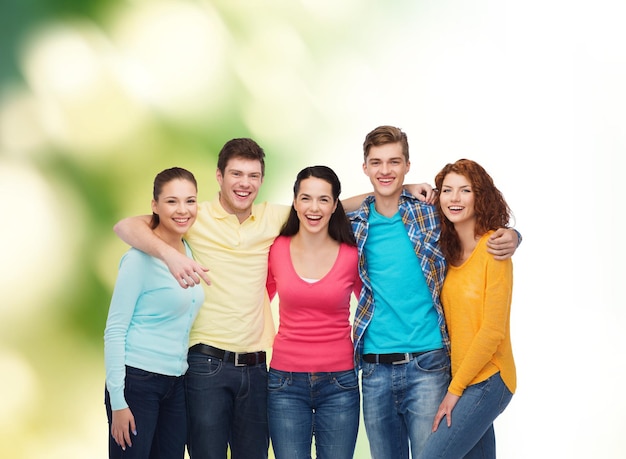 concepto de amistad, ecología y personas - grupo de adolescentes sonrientes de pie y abrazándose sobre fondo verde