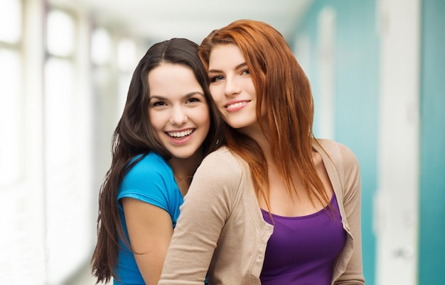 Foto concepto de amistad y gente feliz - dos chicas riéndose abrazándose