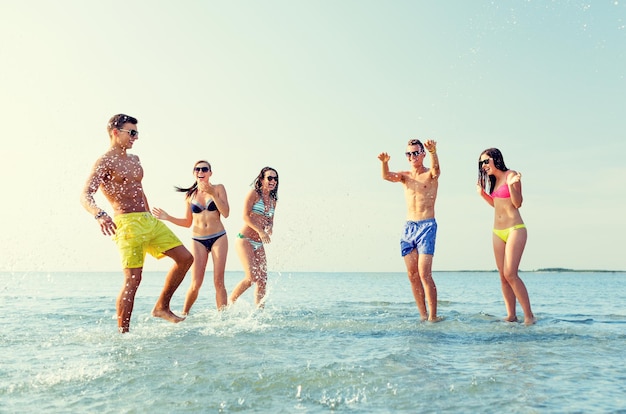 concepto de amistad, mar, vacaciones de verano, vacaciones y personas - grupo de amigos felices divirtiéndose en la playa de verano