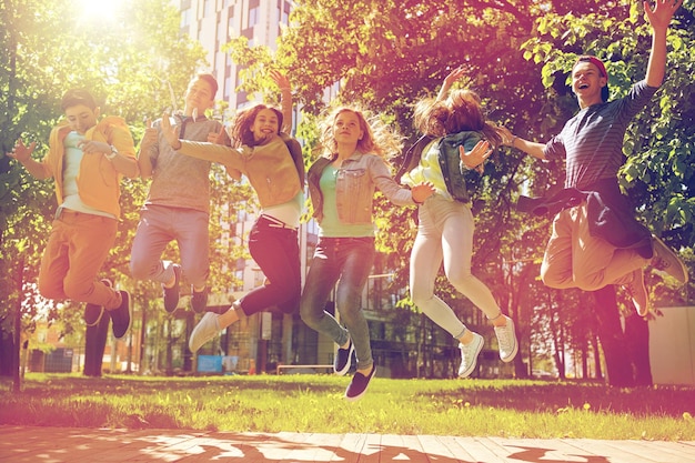 concepto de amistad, movimiento, acción, libertad y personas - grupo de estudiantes adolescentes felices o amigos saltando al aire libre