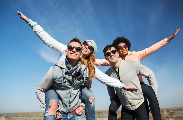 concepto de amistad, ocio y personas - grupo de amigos adolescentes felices con gafas de sol divirtiéndose al aire libre