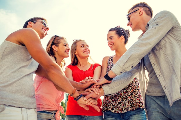 concepto de amistad, ocio, verano, gestos y personas - grupo de amigos sonrientes con las manos en la parte superior de la ciudad