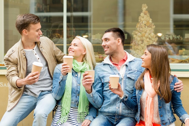 concepto de amistad, viaje, bebida y vacaciones - grupo de amigos sonrientes con café para llevar