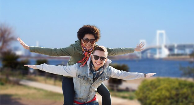 concepto de amistad, viajes, turismo y personas - feliz pareja internacional de adolescentes en tonos divirtiéndose sobre el puente del arco iris en tokio en el fondo de japón