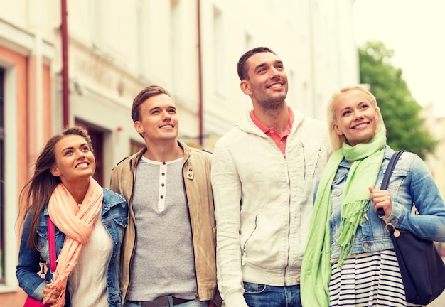 concepto de amistad, viajes y vacaciones - grupo de amigos sonrientes caminando por la ciudad