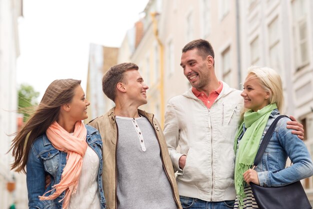 concepto de amistad, viajes y vacaciones - grupo de amigos sonrientes caminando por la ciudad