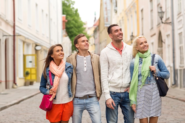 concepto de amistad, viajes y vacaciones - grupo de amigos sonrientes caminando por la ciudad