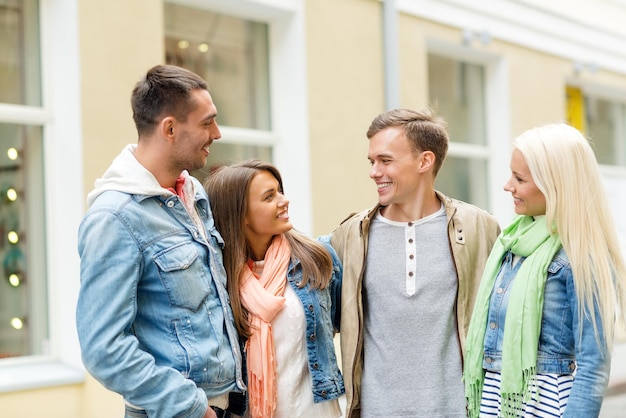 concepto de amistad, viajes y vacaciones - grupo de amigos sonrientes caminando por la ciudad