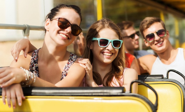 Foto concepto de amistad, viajes, vacaciones, verano y personas - grupo de amigos adolescentes sonrientes con gafas de sol que viajan en autobús turístico