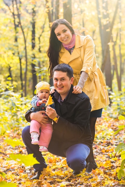 Concepto de amor, paternidad, familia, temporada y personas - pareja sonriente con bebé en el parque de otoño