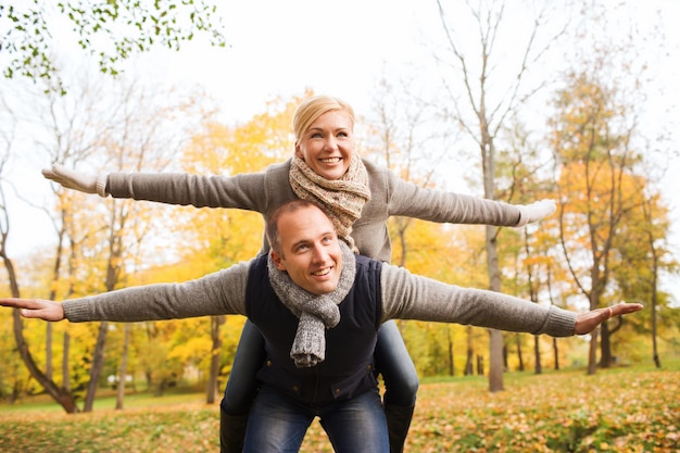 concepto de amor, relación, familia y personas - pareja sonriente divirtiéndose en el parque de otoño