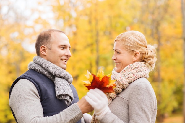 concepto de amor, relación, familia y personas - pareja sonriente en el parque de otoño