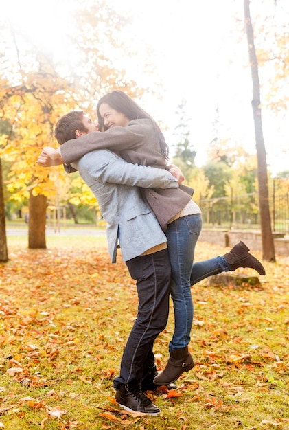 Concepto de amor, relación, familia y personas - sonriente pareja abrazándose en el parque otoño