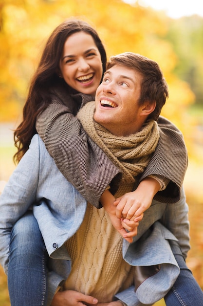 Concepto de amor, relación, familia y personas - sonriente pareja abrazándose en el parque otoño