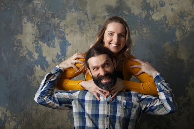 Concepto de amor y relación. Feliz pareja adulta abrazándose, sonriendo y mirando a la cámara, de pie juntos sobre fondo abstracto azul