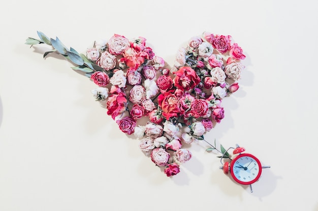 Concepto de amor romántico. Aniversario de la relación. Flor en forma de corazón y reloj en marfil