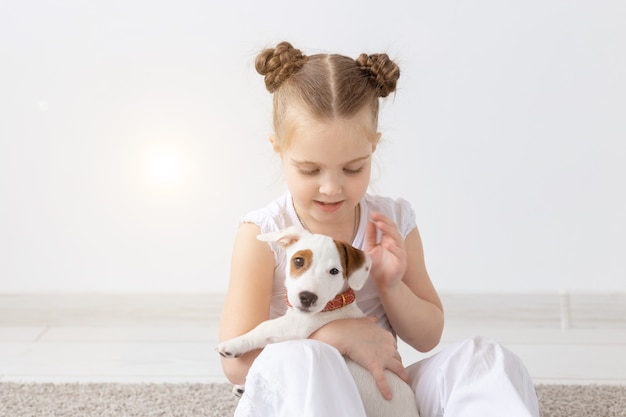 Concepto de animales y mascotas niño niña jugando con cachorro jack russell terrier